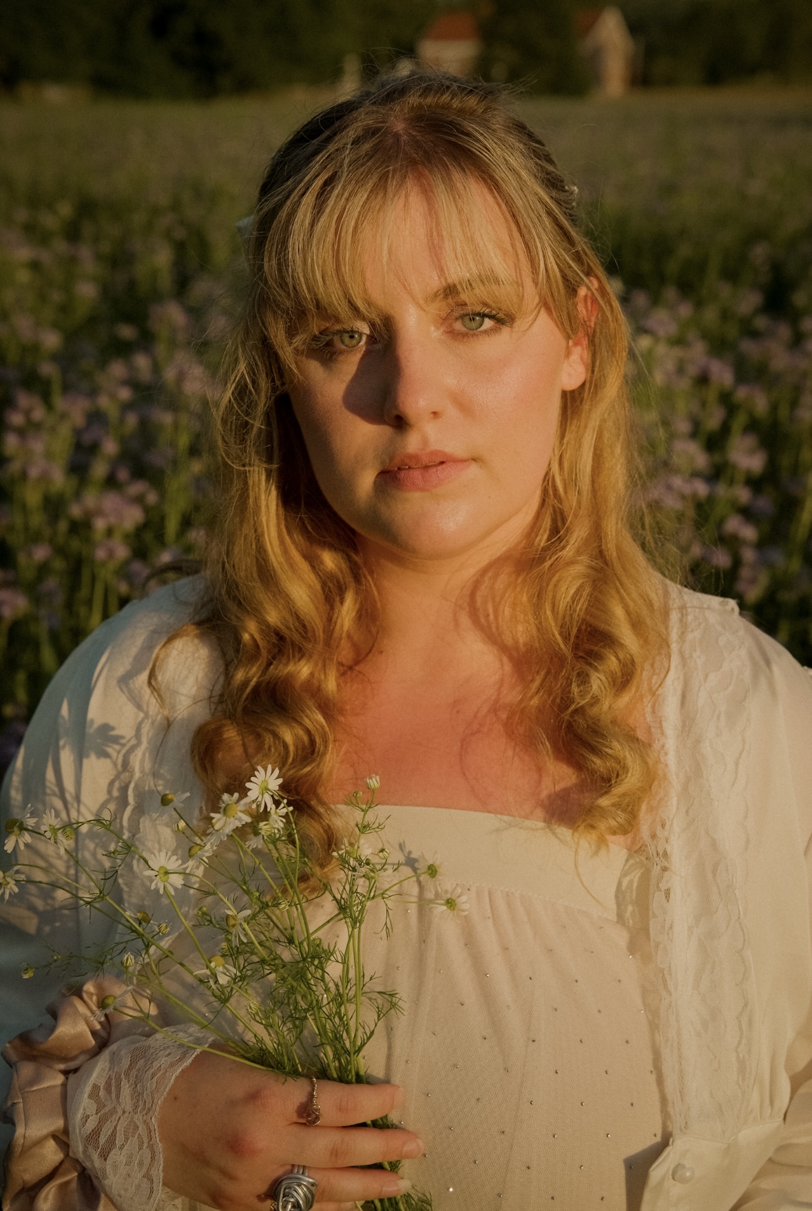 Portrait holding chamomile flowers in a field at sunset